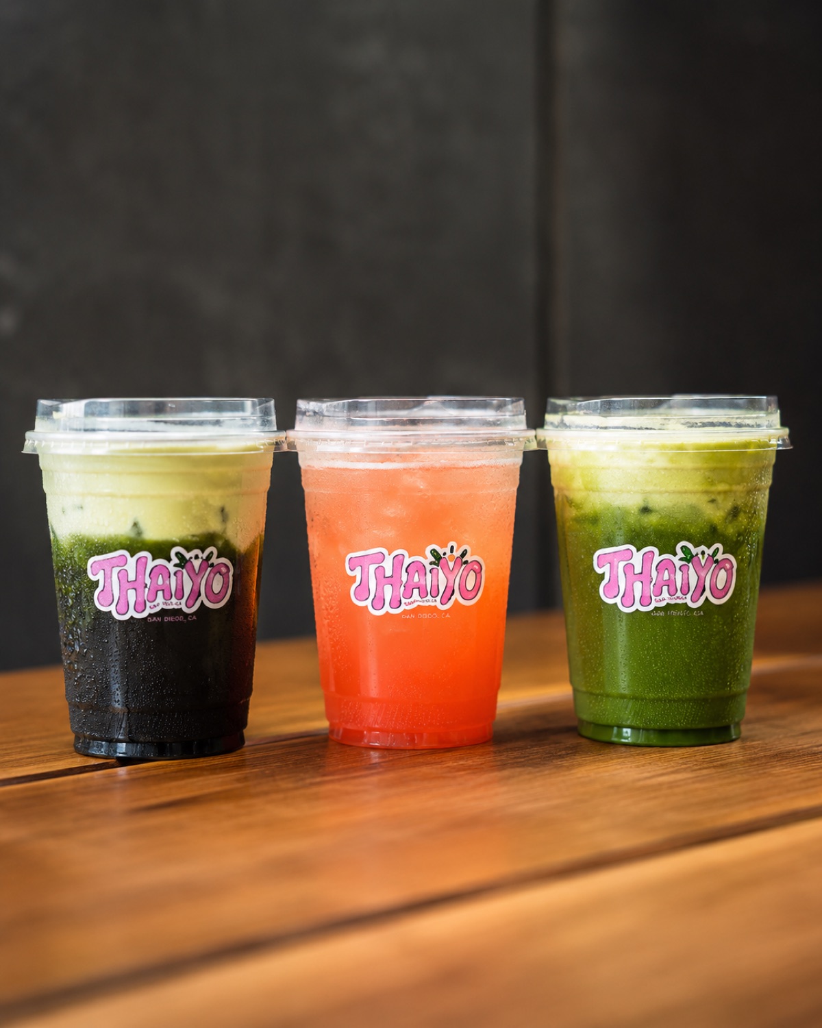 Three Thaiyo drinks lined up on a wood table